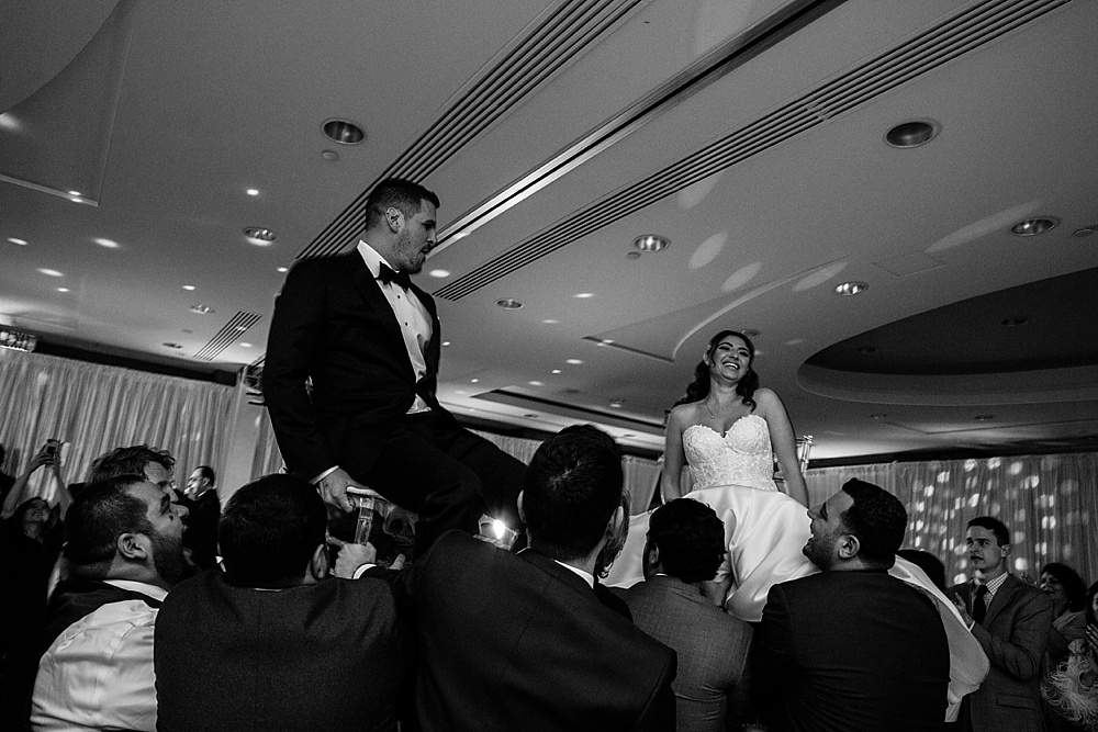 bride and groom carried in chairs