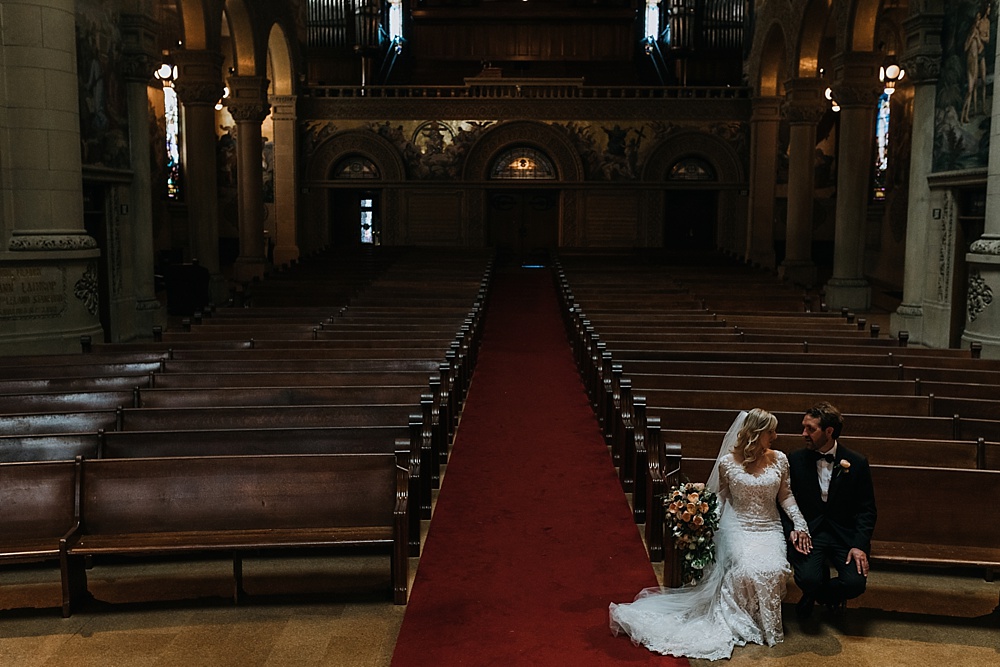 bride and groom sit in pew before stanford memorial church by amy thompson photography 