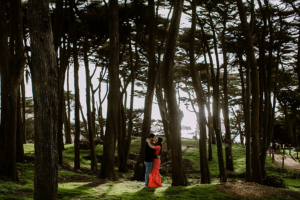 Couple pose by trees near sutro baths for san francisco engagement locations by amy thompson photography