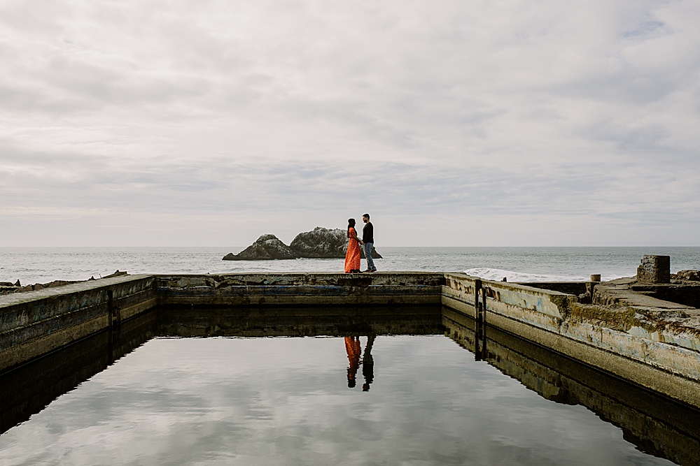 photo of couple by the ocean with reflection at sutro baths engagement session by amy thompson photography