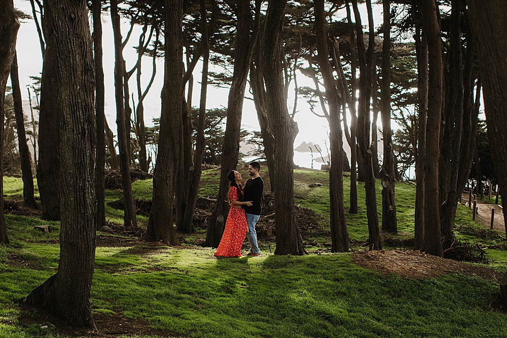 laughing in the forest at sutro baths engagement session by amy thompson photography