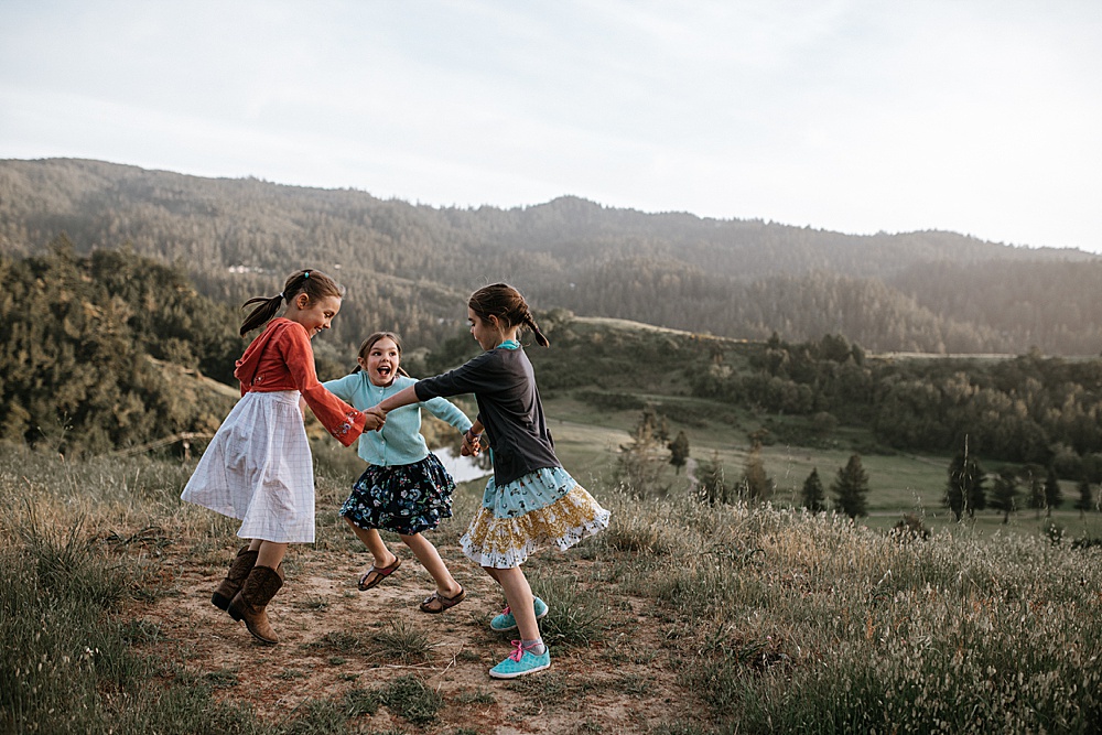 girls dance in a circle during marin family photography shoot by amy thompson photography