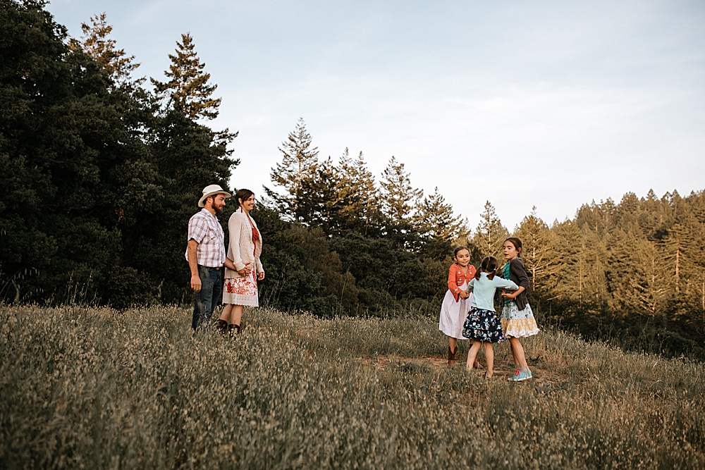 daughters hold hands as parents look on during marin family photography shoot by amy thompson photography