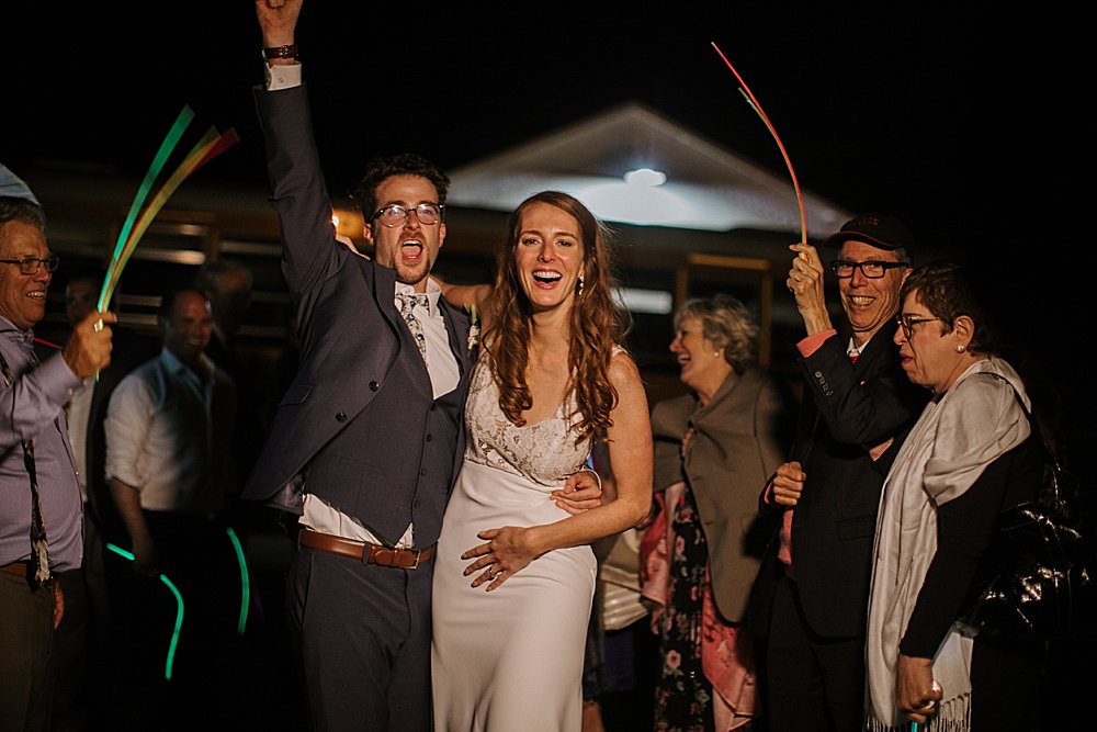 bride and groom laughing at night with glow sticks at Rosewood Events by amy thompson photography