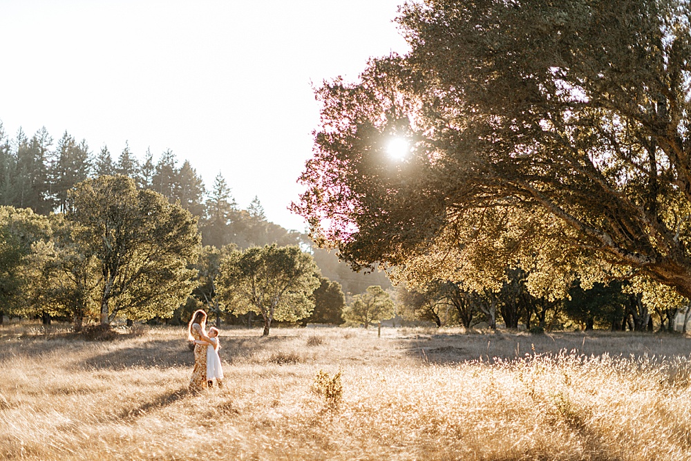 tips for family photos blog image - far off shot of mom and child standing in sunny field hugging