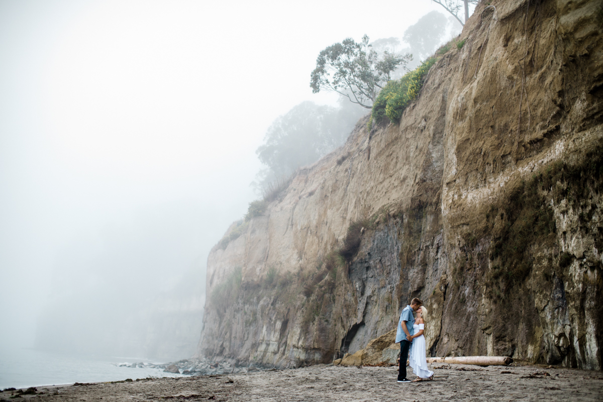 couple kissing on by the cliffs on the foggy santa cruz beach