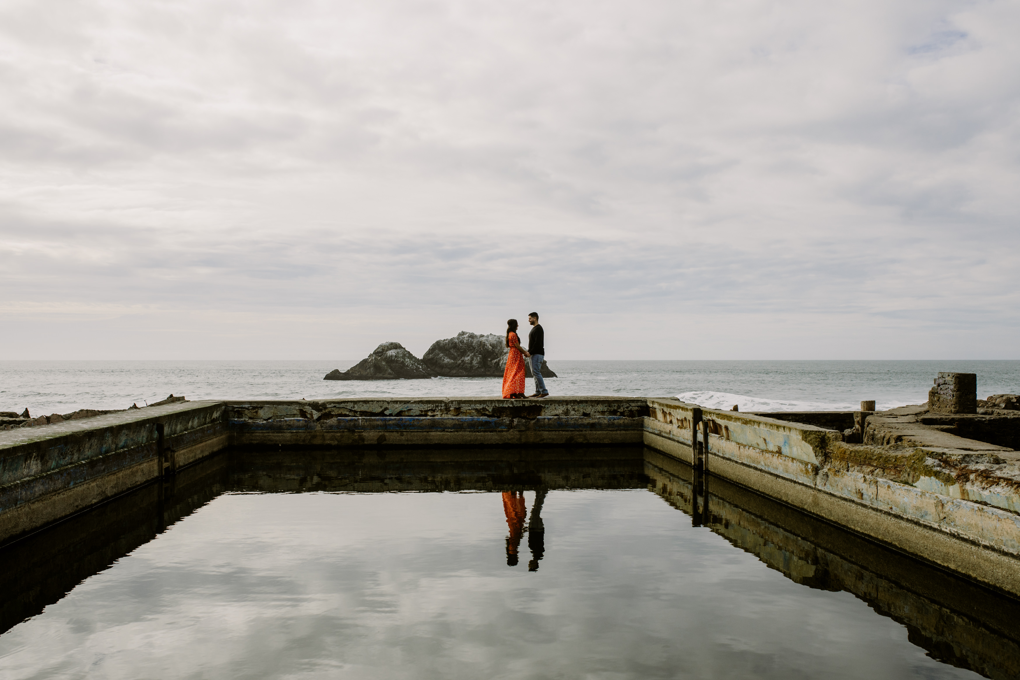 Couple embrace by the ocean during sutro bath engagement session by amy thompson photography
