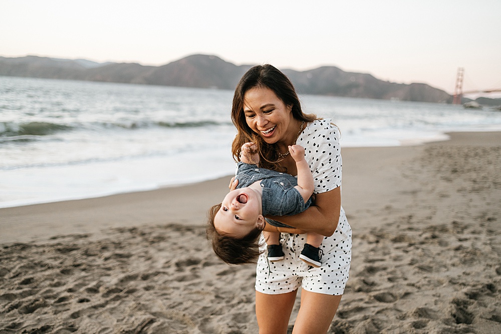 Image for tips for family photos blog - mom holders laughing child on the beach